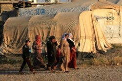 Displaced Iraqi women from the minority Yazidi sect, who fled the Iraqi town of Sinjar, walk at the Khanki camp on the outskirts of Dohuk province, July 31, 2019.