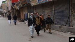 People walk past shops closed because of a strike called to condemn the death of prominent Pashtun rights activist Arman Luni, in Quetta, Pakistan, Feb. 4, 2019. 