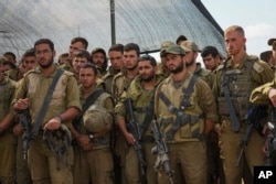 FILE - Israeli soldiers listen to Israel's Defense Minister Yoav Gallant, during his visit to a staging area near the border with the Gaza Strip in southern Israel, Thursday, Oct. 19, 2023.