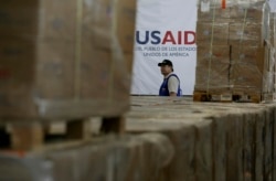 FILE - A man walks past boxes of USAID humanitarian aid at a warehouse at the Tienditas International Bridge on the outskirts of Cucuta, Colombia, Feb. 21, 2019, on the border with Venezuela.