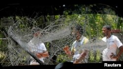 Muslim men stand near a damaged three-wheeler, after a mob attack in a mosque in the nearby village of Kottampitiya, Sri Lanka, May 14, 2019.