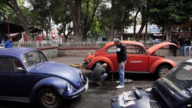 Taxistas que utilizan modelos Beetle de Volkswagen cambian una rueda pinchada en el vecindario de Cuautepec, en Ciudad de México, el viernes 21 de junio de 2024