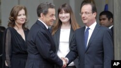 El saliente presidente, Nicolas Sarkozy, y el entrante mandatario, François Hollande, escoltados por la compañera de Hollande, Valerie Trerweiler, y Carla Bruni-Sarkozy durante la ceremonia de traspaso del mando.