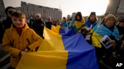 Sejumlah pengunjuk rasa membawa bendera nasional Ukraina saat melakukan protes menentang perang Rusia di Ukraina, menandai peringatan pertama agresi skala penuh Rusia, di Bukares, Rumania, 24 Februari 2023. (Foto: Andreea Alexandru/AP)