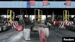 FILE - Workers clean up the Lekki toll gate, the site where soldiers had opened fire on protesters rallying against alleged police brutality, in Lagos, Nigeria, Oct. 24, 2020. 