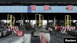 FILE - Workers clean up the Lekki toll gate, the site where soldiers had opened fire on protesters rallying against alleged police brutality, in Lagos, Nigeria, Oct. 24, 2020. 