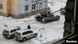 FILE - Organization for Security and Cooperation in Europe (OSCE) vehicles are seen behind tanks in the government-held industrial town of Avdiivka, eastern Ukraine, Feb. 1, 2017.