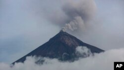 FILE - A plume of smoke and ash rises from the Volcano of Fire, June 15, 2018, as seen from San Miguel Los Lotes, Guatemala. Guatemala's Volcano of Fire, one of the region's most active, started spewing ash again Friday.