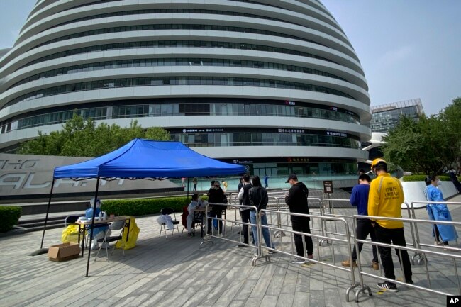 Warga antre untuk tes COVID-19 di lokasi pengujian di kompleks perkantoran di Beijing, Jumat, 29 April 2022. (Foto: AP)
