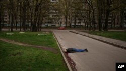 FILE - The body of a man killed during a Russian bombardment lies on a street in a residential neighborhood in Kharkiv, Ukraine, April 19, 2022.
