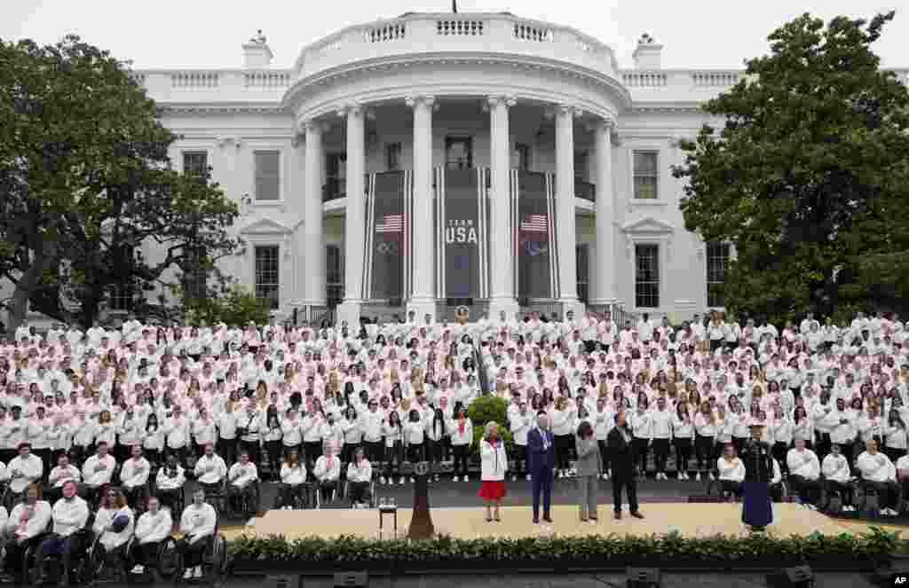 On stage from left, first lady Jill Biden, President Joe Biden, Vice President Kamala Harris and second gentleman Doug Emhoff stand for the national anthem during an event with the Tokyo 2020 Summer Olympic and Paralympic Games, and Beijing 2022 Winter Olympic and Paralympic Games, on the South Lawn of the White House in Washington.