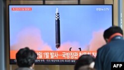 People watch a television screen showing a news broadcast with file footage of a North Korean missile test, at a railway station in Seoul on May 4, 2022. - North Korea fired a ballistic missile on May 4, South Korea's military said, just a week after lead