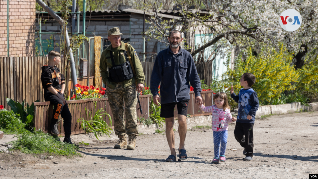 Un chico del lugar saluda a los militares desde la defensa territorial mientras pasa por el sitio del ataque aéreo ruso al distrito civil en Zaporiyia.