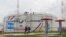 FILE - Workers walk past a storage tank at the Kaleikino oil pumping station of Transneft Kama Region near Almetyevsk, Russia, April 27, 2022.