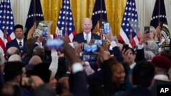 President Joe Biden, center, on stage with Talib M. Shareef, right, President and Imam of the historic, Nation's Mosque, Masjid Muhammad in Washington, and first lady Jill Biden, left, celebrate Eid al-Fitr at the White House, May 2, 2022.