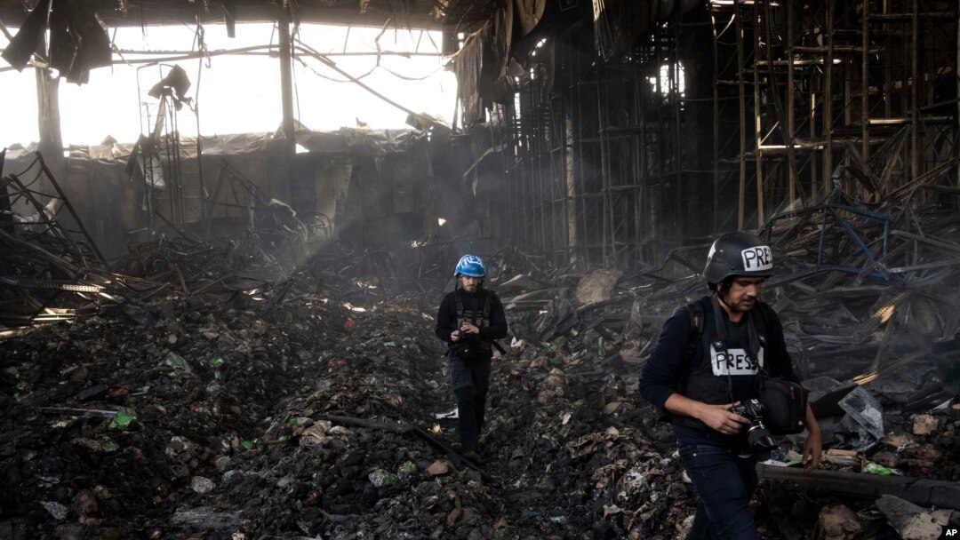 Wartawan berjalan di dalam gudang yang hancur yang digunakan untuk menyimpan makanan, setelah serangan dari Rusia di Brovary, di pinggiran Kyiv, Ukraina, Selasa, 29 Maret 2022. (Foto: AP/Rodrigo Abd)