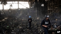 Wartawan berjalan di dalam gudang yang hancur yang digunakan untuk menyimpan makanan, setelah serangan dari Rusia di Brovary, di pinggiran Kyiv, Ukraina, Selasa, 29 Maret 2022. (Foto: AP/Rodrigo Abd)