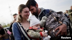 A family of Ukrainian evacuees from Mariupol embraces after arriving at a registration center for internally displaced people in Zaporizhzhia, Ukraine, May 3, 2022.