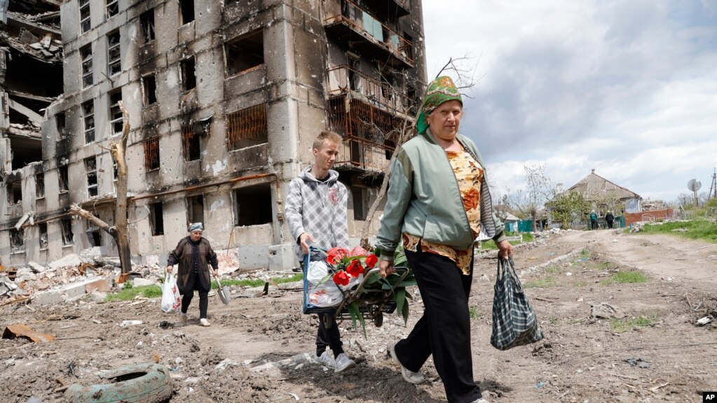 People walk past a destroyed apartment building in Mariupol, in territory under the government of the Donetsk People's Republic, eastern Ukraine, May 2, 2022. 