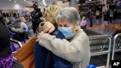 Seorang perempuan dari Los Angeles berpelukan dengan anggota keluarganya di bandara Auckland, Selandia Baru setelah pembukaan kembali perbatasan udara hari Senin, 2 Mei 2022. 