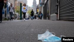 A pair of discarded face masks sit on the side walk in New York City, New York, May 2, 2022. 