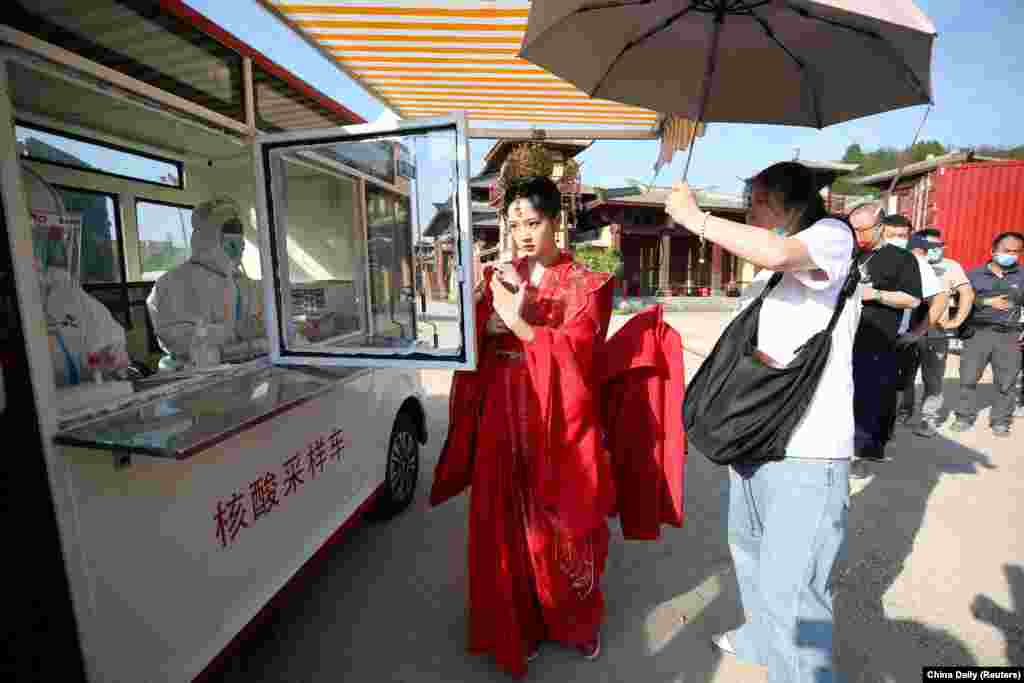 Crew members line up to get tested for the COVID-19 at a mobile nucleic acid testing vehicle inside Hengdian World Studios in Hengdian, Zhejiang province, China, May 3, 2022.