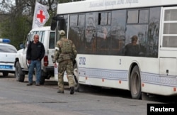 A service member of pro-Russian troops walks next to a bus as civilians from Mariupol, including evacuees from Azovstal steel plant, travel in a convoy to Zaporizhzhia, during Ukraine-Russia conflict in the Donetsk Region, Ukraine May 2, 2022.