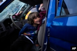A child sits in a car as his family waits to be processed upon their arrival from Mariupol at a reception center for displaced people in Zaporizhzhia, Ukraine, Monday, May 2, 2022. (AP Photo/Francisco Seco)