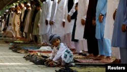 A boy plays as people attend Eid al-Fitr prayers to mark the end of the holy fasting month of Ramadan in Peshawar, Pakistan, May 2, 2022. Muslims across India also marked Eid al-Fitr on Tuesday by offering prayers outside mosques.