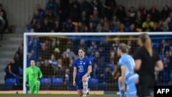 FILE - Players take a knee to show their support of Ukraine, follwing the country invasion by Russia, prior to the start of the English Women's League Cup Final match between Chelsea and Manchester City in Wimbledon on March 5, 2022.