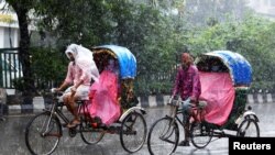 বাংলাদেশের ঢাকায় বৃষ্টিতে যাত্রীরা রিকশায় চড়ে যাচ্ছে। ১৩ সেপ্টেম্বর, ২০২০। (ফাইল ছবি) 