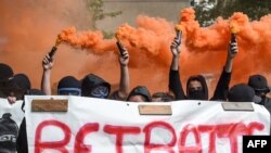 Protesters hold smoke bombs and a banner reading &quot;retirement at 20&quot; as they take part in the traditional May Day rally in Nantes, western France.
