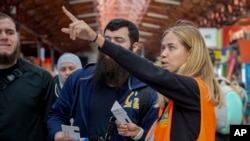 Ukrainian volunteer Anastasiia Haiduk points to a departure board for Ukrainian refugees at Bucharest's North Railway Station in Romania, April 23, 2022.
