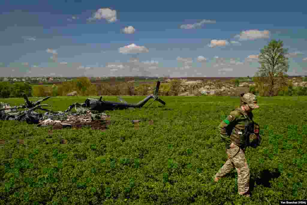 Ukrayna əsgəri Xarkiv yaxınlığında döyüş zamanı rus helikopterinin vurulduğu yerdən uzaqlaşır