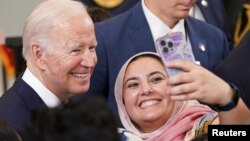 Seorang perempuan Muslim mengajak Presiden AS Joe Biden untuk swafoto pada perayaan Idul Fitri di Gedung Putih, 2 Mei 2022. 