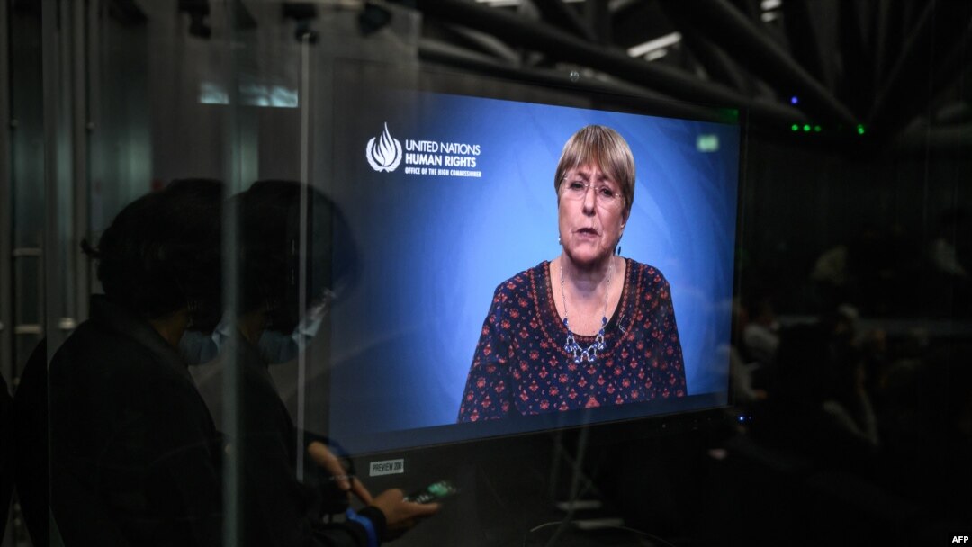 A journalist wearing a face mask as a preventive measure against COVID-19 looks at her mobile phone next to a TV monitor showing a speech by United Nations High Commissioner for Human Rights Michelle Bachelet during World Press Freedom Day in Geneva, May 3, 2022.