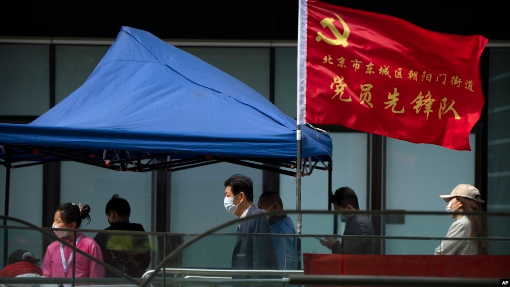 人们在北京市东城区插着一面中共旗帜的新冠病毒核酸检测点排队等候检测。（2022年4月29日）(photo:VOA)