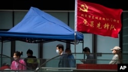人们在北京市东城区插着一面中共旗帜的新冠病毒核酸检测点排队等候检测。（2022年4月29日）