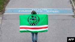 FILE - A young Chechen carries a Chechnya's flag as he walks near the Danube Canal in Vienna on Feb. 4, 2022.