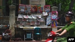 Một nhân viên công an lái xe ngang qua một sạp bán báo trên đường phố ở trung tâm Hà Nội. Việt Nam nằm trong nhóm 10 quốc gia "tồi tệ nhất trên thế giới" về tự do báo chí, theo đánh giá của RSF. 