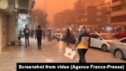 People are seen on a road Sunday during a sandstorm in Iraq's capital, Baghdad, Iraq, May 1, 2022. Iraq was yet again covered in a thick sheet of orange as it suffered the latest in a series of dust storms that have become increasingly common.