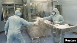 FILE - Workers at the South African pharmaceutical major Aspen Pharmacare pass a bottle at its Johnson & Johnson COVID-19 vaccine facility in Gqeberha, South Africa, Oct. 25, 2021.