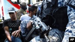 FILE - Men are detained by the police, suspects in a homicide near a market in San Salvador, El Salvador, March 27, 2022.