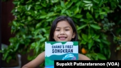 An American-Thai YouTuber, Pailain Taylor (7 years old), holds a book" Chang's First Songkran "after an interview with VOA Thai in Los Angeles, CA.