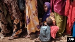 FILE - A woman holds her child as she waits for high nutrition foods and medical consultations at Tawkal 2 Dinsoor camp for internally displaced persons (IDPs) in Baidoa, Somalia, Feb. 14, 2022.