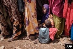 FILE - A woman holds her child as she waits for high nutrition foods and medical consultations at Tawkal 2 Dinsoor camp for internally displaced persons (IDPs) in Baidoa, Somalia, Feb. 14, 2022.