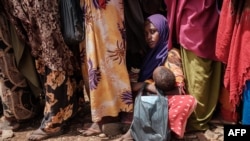 FILE - A woman holds her child as she waits for high-nutrition foods and medical consultations at Tawkal 2 Dinsoor camp for internally displaced persons in Baidoa, Somalia, Feb. 14, 2022. 