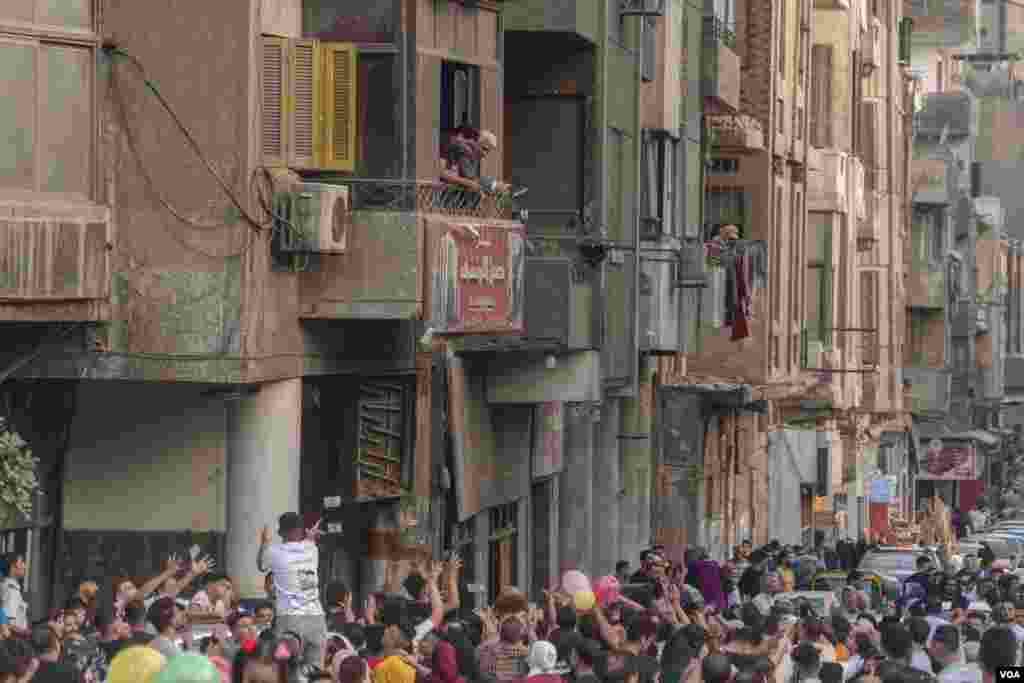 After Eid al-Fitr prayers, a man blissfully scatters banknotes of five Egyptian pounds on worshippers from his office window, Islamic Cairo, May 2, 2022. (Hamada Elrasam/VOA)