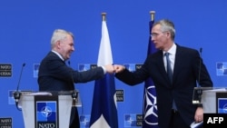 NATO Secretary General Jens Stoltenberg (R) and Finland Ministers for Foreign Affairs Pekka Haavisto (L) bump fists after holding a joint press conference after their meeting at the Nato headquarters in Brussels on January 24, 2022. (Photo by JOHN THYS / AFP) 