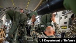 A US Marine helps direct a forklift carrying an M777 howitzer bound for Ukraine onto a C-17 Globemaster III at March Air Reserve Base, CA., Apr. 27, 2022.